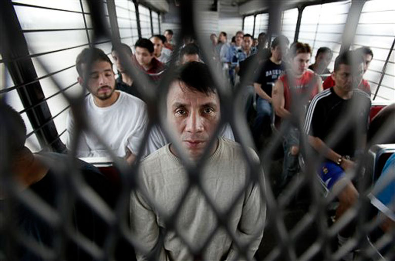 Immigrants on a U.S. Immigration and Customs Enforcement bus heading for deportation / AP Photo/LM Otero