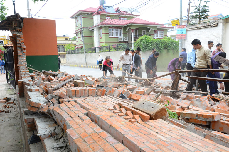 people clearing bricks from a fallen wall following April Nepal quake / Jeevan Ale