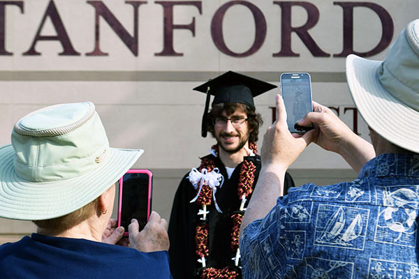A graduate is photographed by his family at Commencement.