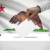 hand putting a ballot in ballot box with California flag in background