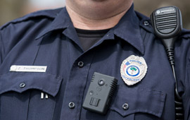 Closeup of police officer's chest showing badge, radio and body camera 