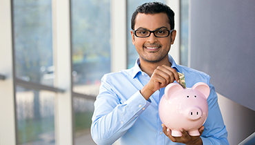 Young Indian male with money in piggy bank
