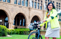 Female staffer next to her bicycle with helmet, in front of Jordan Hall.