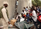 Residents fight for food as a police officer watches them after a major earthquake hit the Haitian capital Port-au-Prince, Haiti.