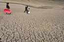 A family carry containers as they walk on a partially dried-up ...