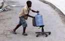 A child pushes a chair with a bottle at a street in Port-au-Prince ...