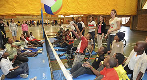 Photo of students and community volunteers learning the sport of sitting volleyball