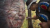 A well-wisher writes a message on a poster of Nelson Mandela on which she and others have written their messages of condolence and support, in the street outside his old house in Soweto, Johannesburg, South Africa, Dec. 6, 2013.