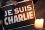 A man holds a candle and placard that reads in French, 