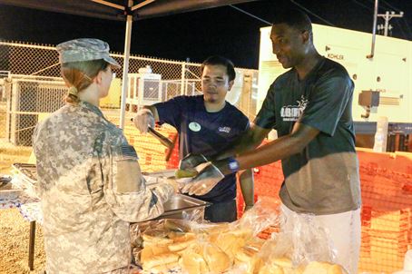 Morale, Welfare & Recreation’s Liberty Center employees fill a Joint Task Force Guantanamo Trooper’s plate with a hamburger and hotdog during a “We Feed You, You Feed Back” burger burn on July 27, 2017 here. The Liberty Centers hosted the event to get feedback from the night shift workers on how to better accommodate programs for their schedules.