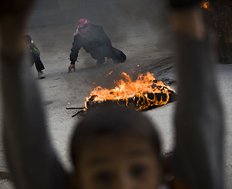 Palestinian children are seen during clashes with Israeli forces, not pictured, in the West Bank city of Hebron, Friday, March 19, 2010. Palestinians in east Jerusalem and the West Bank lobbed rocks at Israeli security forces, set garbage bins and tires ablaze and torched an Israeli flag in a new outbreak of violence over contested Jerusalem building plans and unsubstantiated rumors about threats to the city's holiest shrine. (AP Photo/Bernat Armangue)