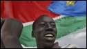 Residents of Abyei, with a southern Sudan flag in background, celebrate the decision of the Hague-based Permanent Court of Arbitration 