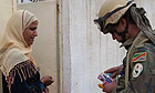 Troops hand out contact number cards to Iraqi residents