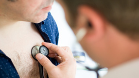 Men's health (A doctor placing a stethescope on a man's chest)