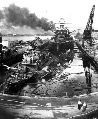 The wrecked destroyers USS Downes (DD-375) and USS Cassin  (DD-372) in Drydock One at the Pearl Harbor Navy Yard, soon after the end of the Japanese air attack. Cassin has capsized against Downes. USS Pennsylvania (BB-38) is astern, occupying the rest of the drydock. The torpedo-damaged cruiser USS Helena (CL-50) is in the right distance, beyond the crane. Visible in the center distance is the capsized USS Oklahoma (BB-37), with USS Maryland (BB-46) alongside. Smoke is from the sunken and burning USS Arizona (BB-39), out of view behind Pennsylvania. USS California (BB-44) is partially visible at the extreme left. This image has been attributed to Navy Photographer's Mate Harold Fawcett.  Official U.S. Navy Photograph, National Archives Collection.