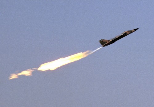 An air-to-air right side view of an F-111 aircraft trailing flames during a demonstration for Open House '83. Photographer's Name: Harrison Location: EDWARDS AIR FORCE BASE Date Shot: 10/30/1983