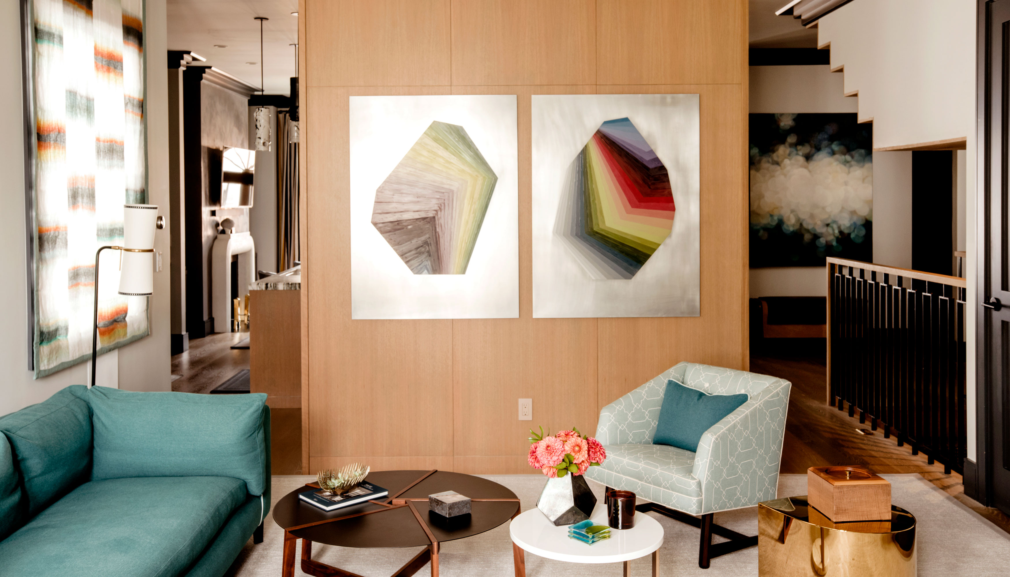 A living area with a couch, armchair, tables, and lamp. There are works of art on the walls.