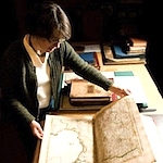 Julie Sweetkind-Singer, head librarian of the Branner Earth Sciences Library, looks through a world atlas published in France in 1742, the Atlas Nouveau by de Lisle, part of the David Rumsey Map Collection. 