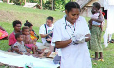 A village nurse in Vanuatu oversees the weighing of children before they receive vaccinations