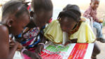 A group of girls in Liberia reads a poster with Ebola prevention information