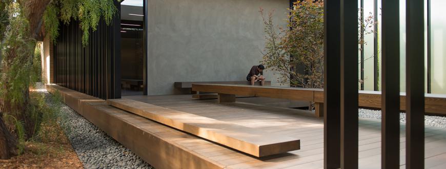Student reading in the external courtyard of Japanese-influenced modern architecture