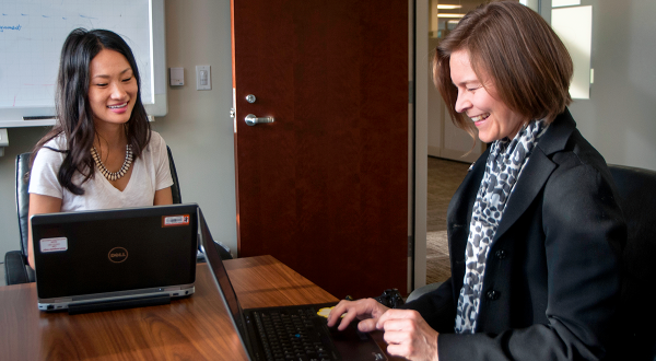 A female colleague and her manager on laptops in conference room