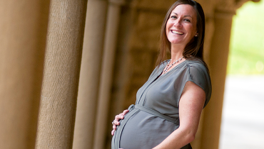 A beaming pregnant female staff member cradling her belly