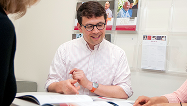 Male staff member looking over documents with two colleagues