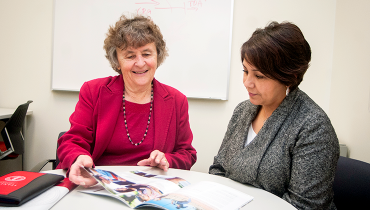 Senior female staff member explaining benefits brochures to colleague