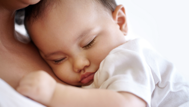 Baby resting arm and body against mother's neck.