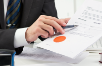 Male notary in business suit pointing where to sign on an official document.