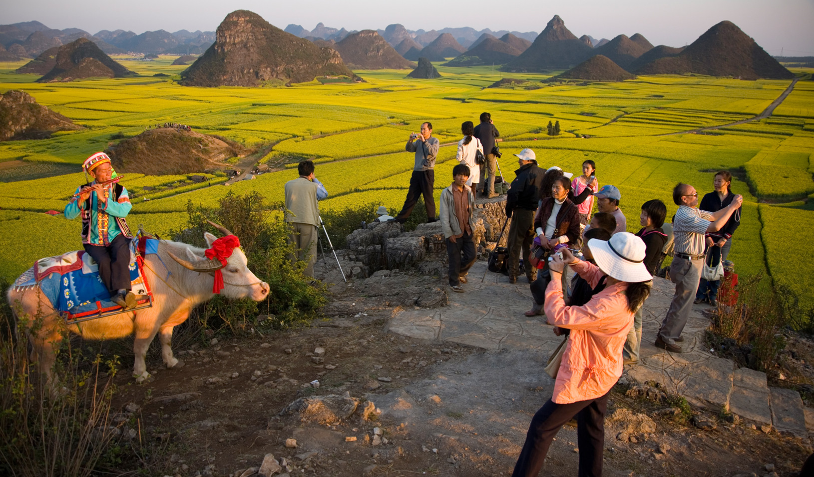 Tourists photograph a costumed flutist in Luoping, Yunnan Province (National Geographic Creative photo by George Steinmetz)