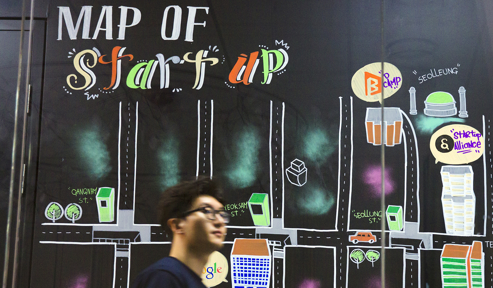 Man walking past a wall painting labeled “Map of Start-up” at the Google Campus start-up space in the Gangnam district of Seoul. | Reuters/Thomas Peter
