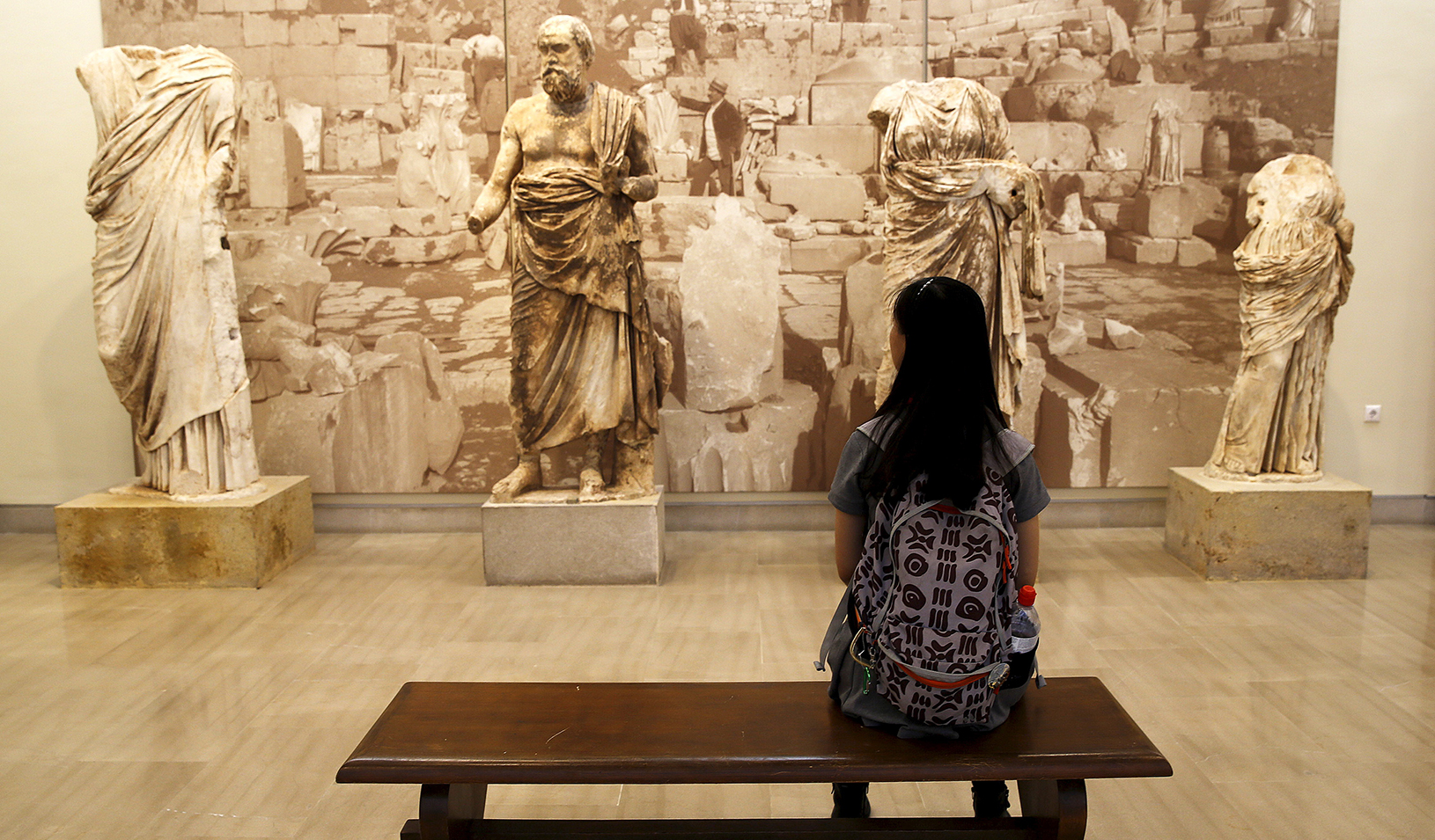 Woman sitting on a museum bench looking a sculptures | Reuters/Yannis Behrakis