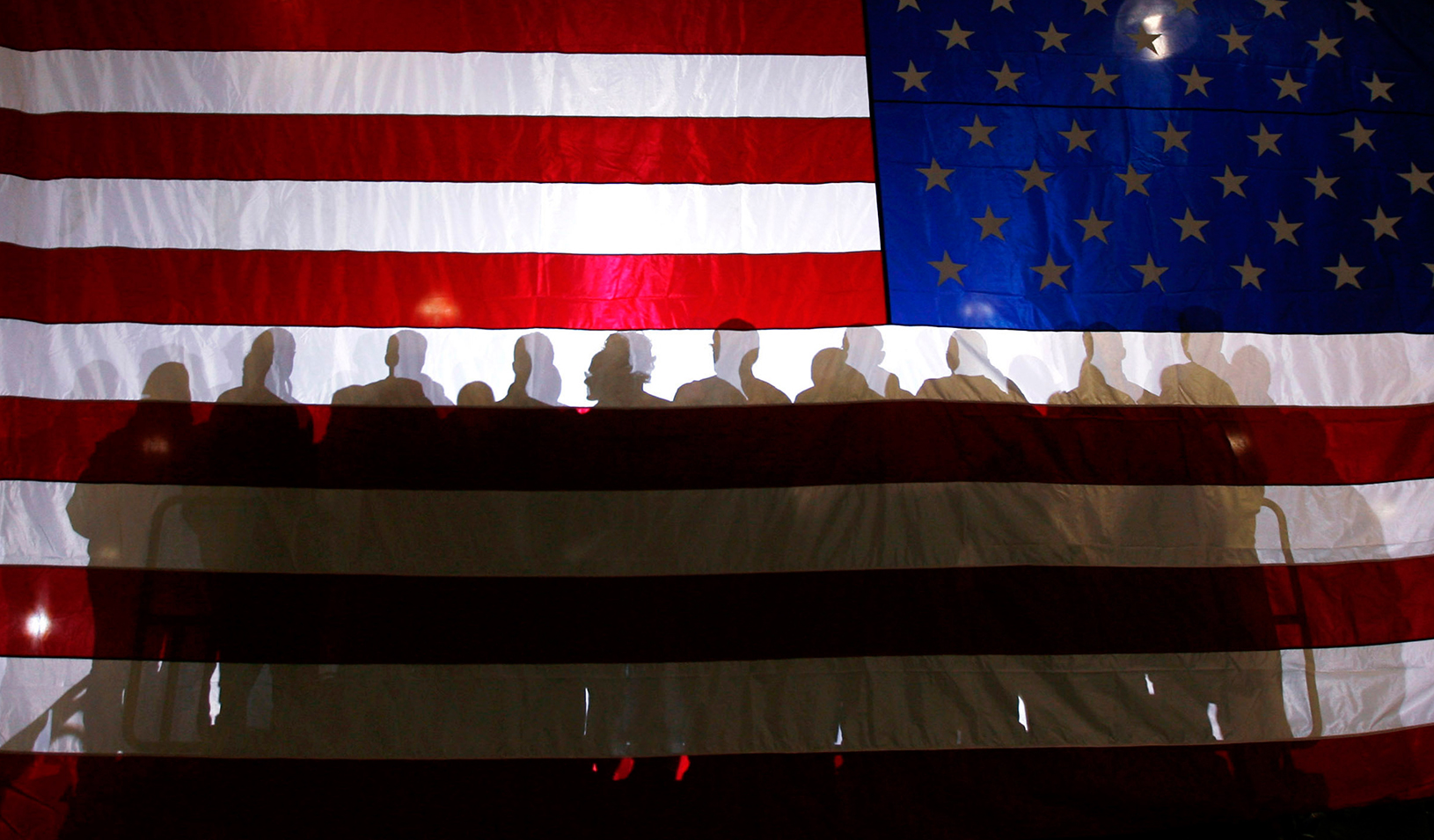 Shadows of a group of people against an American flag backdrop