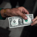 Hands exchanging a dollar bill