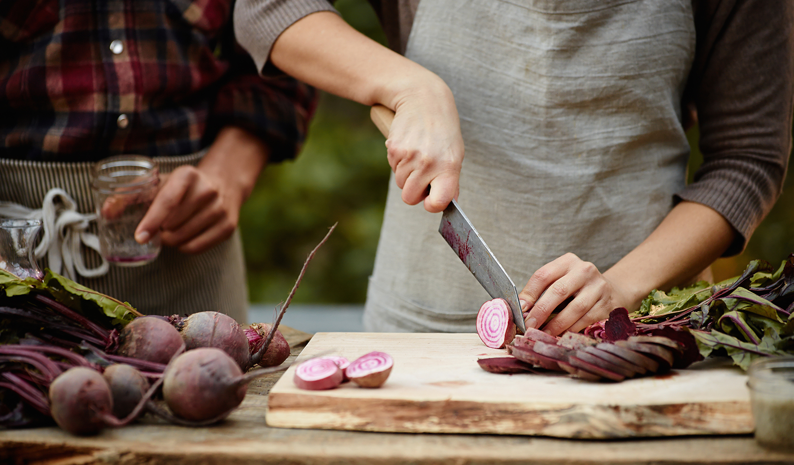Chef uses a knife to slice vegetables on a cutting board. | iStock/Chris Gramly
