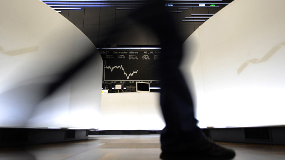 man walking in front of trading monitor