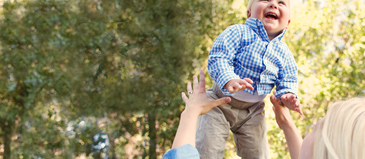 Young boy smiling as he's being lifted into the air