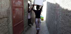 A resident of a slum in Cap Haitien, Haiti carries a dry toilet developed by Stanford engineers.