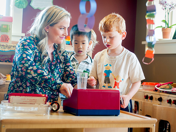 Female staff member showing two young boys a toy machine