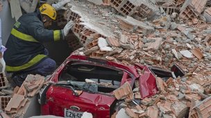 A firefighter searches for survivors of a building collapse in sao Paulo on 27 August 2013