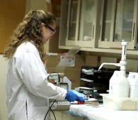photo of woman in lab coat working with scientific equipment