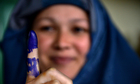 An Afghan voter shows her inked finger after she cast her ballot at a local polling station in Kabul
