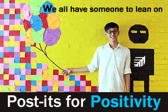 Boy standing in front of a wall covered with post its