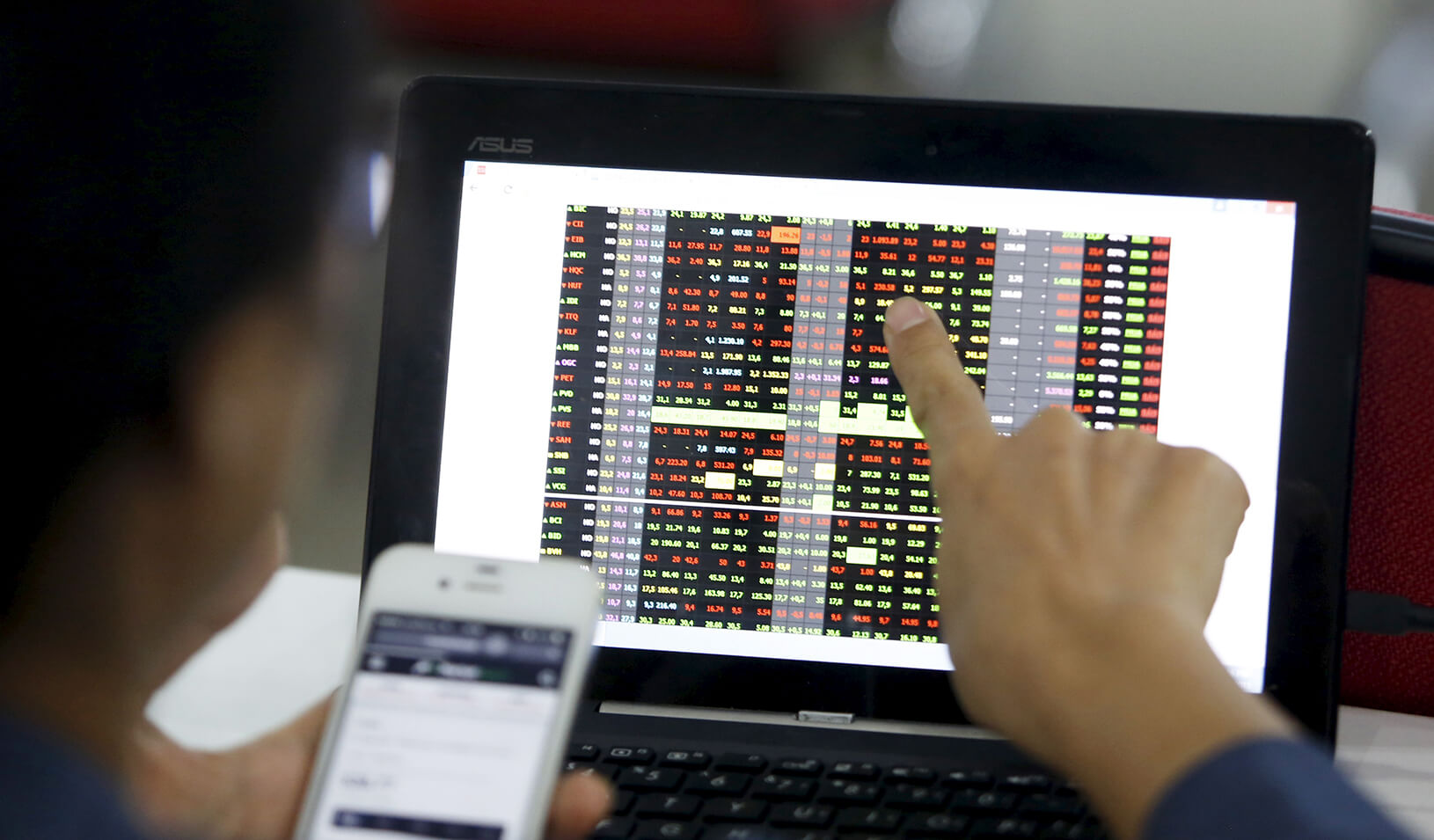 user pointing at computer screen showing stock prices | Reuters/Kham