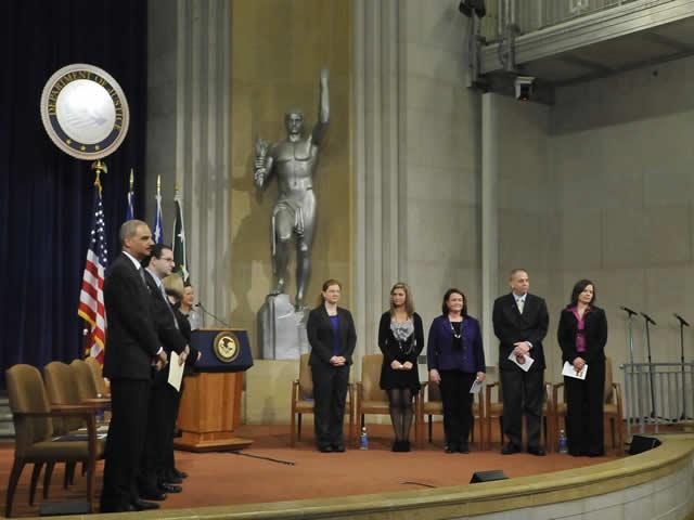 Department executives and panel members stand for the opening of the Stalking Awareness Event.