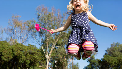 Girl outside, mid-jump.