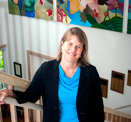 Portrait of staffer Megan Fogarty on staircase in front of paintings on wall
