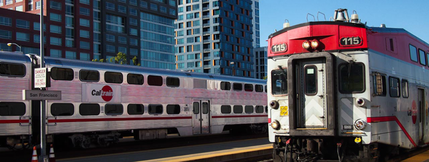 Caltrain arriving to station in San Francisco, tracks next to skyscrapers.